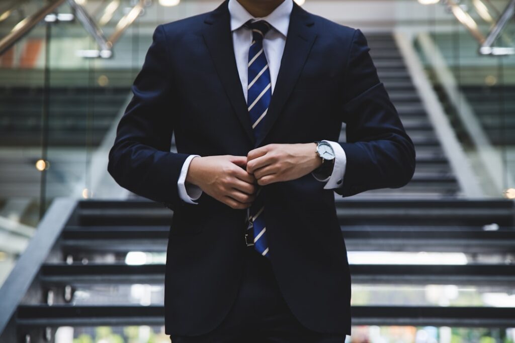 Business professional buttoning suit jacket — building authority lowers client acquisition costs